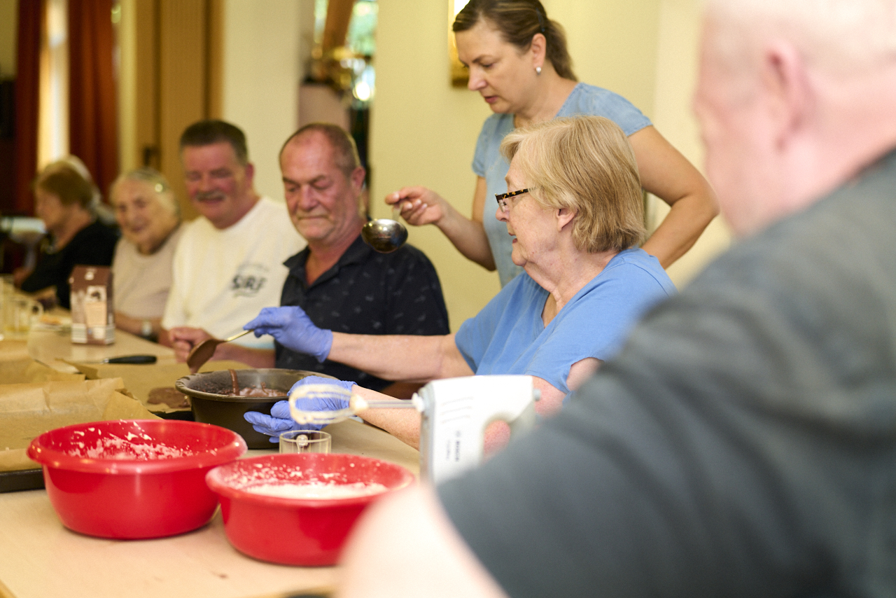 Gruppe von Senioren mit Betreuerin beim Backen